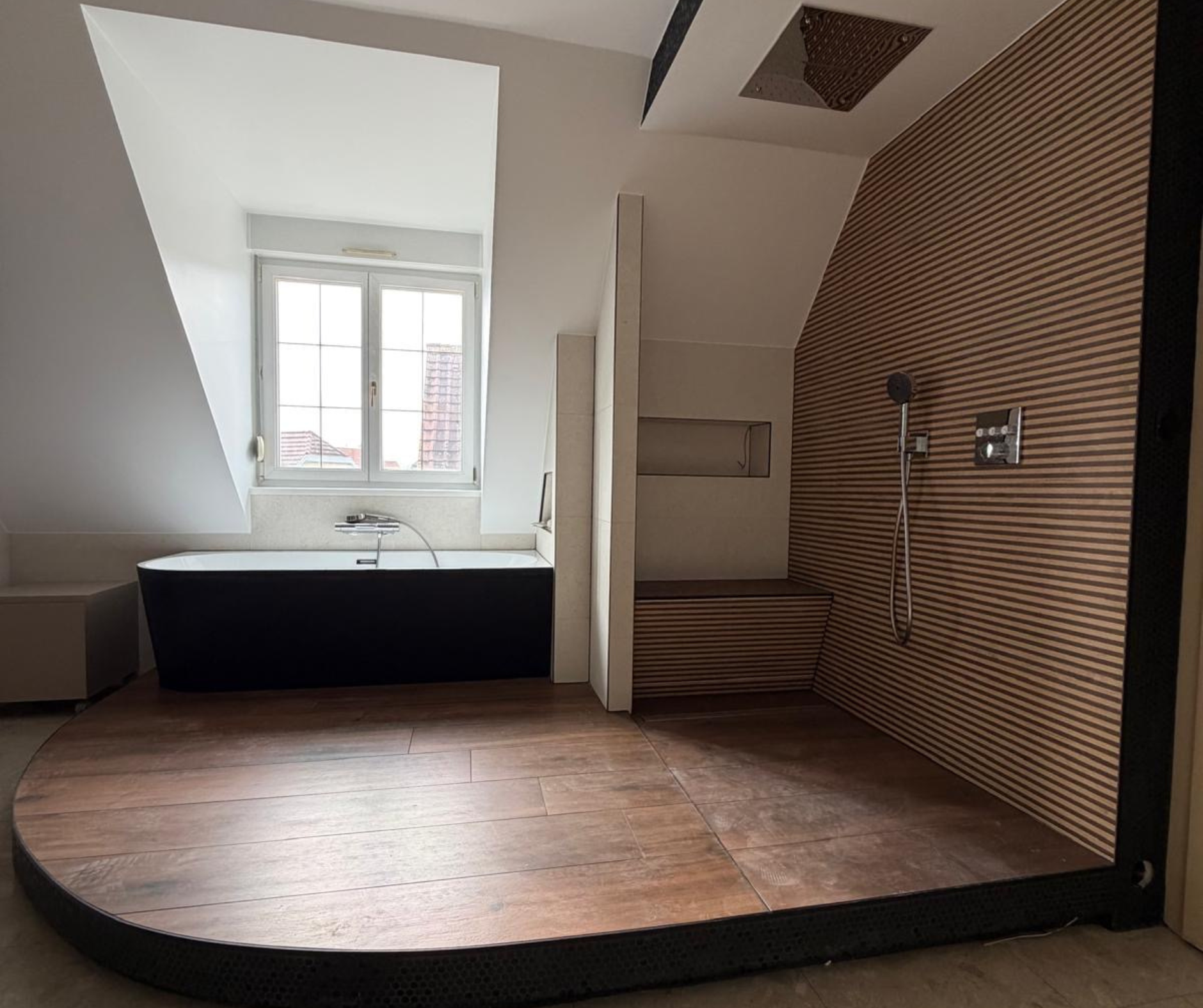 Espace détente avec baignoire îlot noire et blanche Le Square et robinetterie moderne, baignée de lumière naturelle sous lucarne, aménagement durable pour salle de bain.
